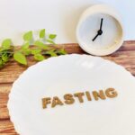 「FASTING」と書かれた皿と時計が並ぶ断食を象徴する画像