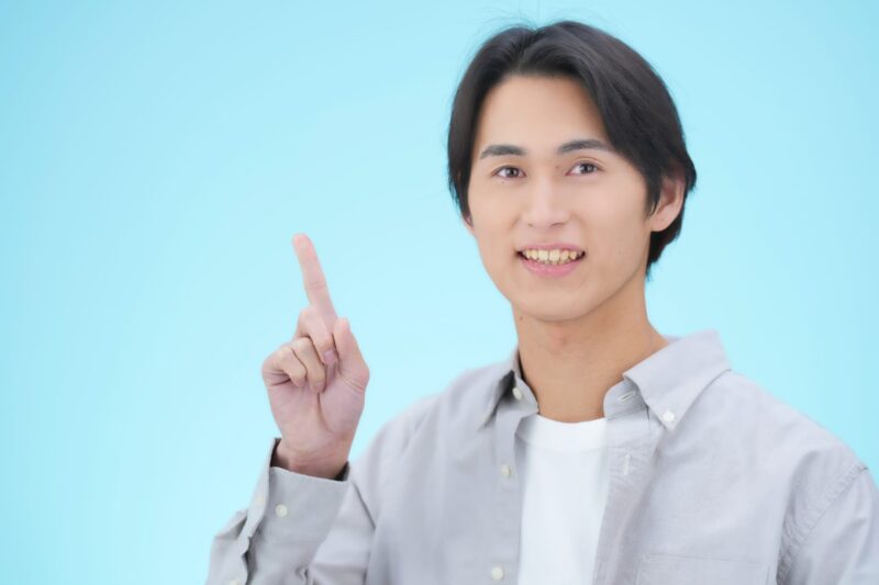 指を立てて案内する若い男性の画像