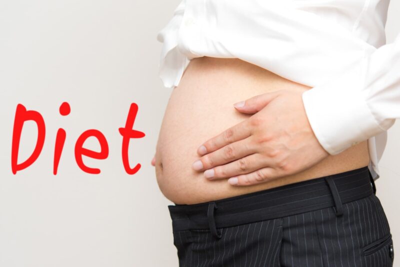 お腹を押さえている中年男性のダイエットを示唆する画像