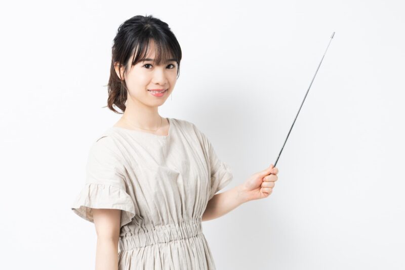 指示棒を使って説明する講師風の女性をイメージできる画像