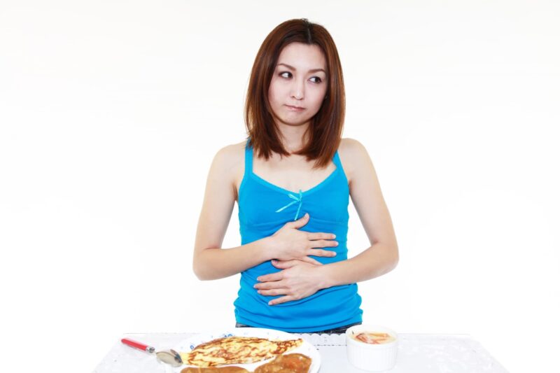 食後の不調に戸惑う女性をイメージできる画像