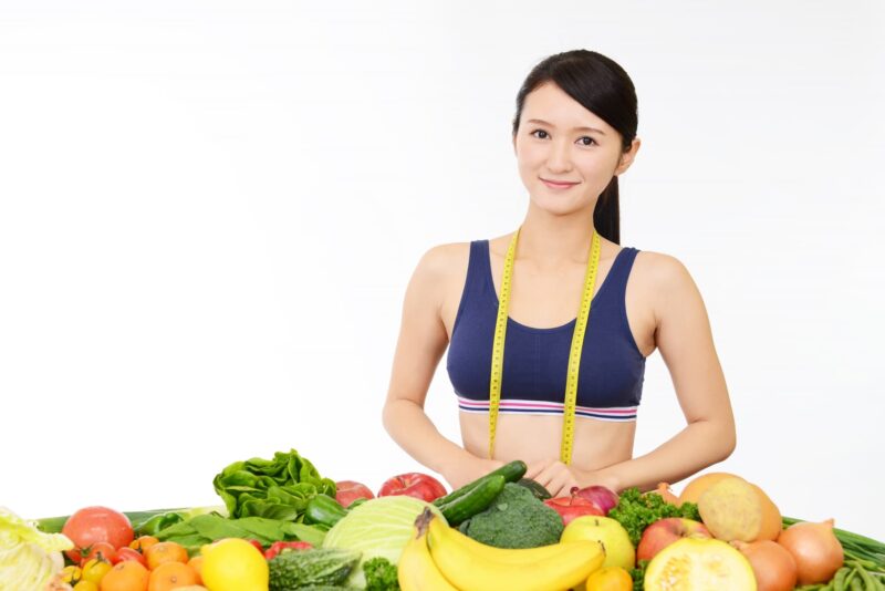 野菜と一緒に写る健康的な女性の画像