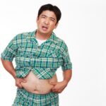 お腹を出して肥満に悩む男性の画像