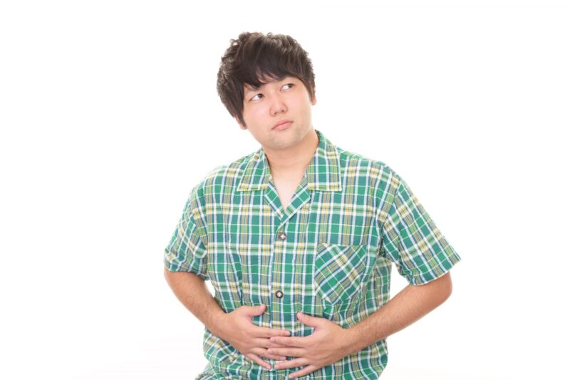 お腹を押さえて苦しそうにしている男性の画像