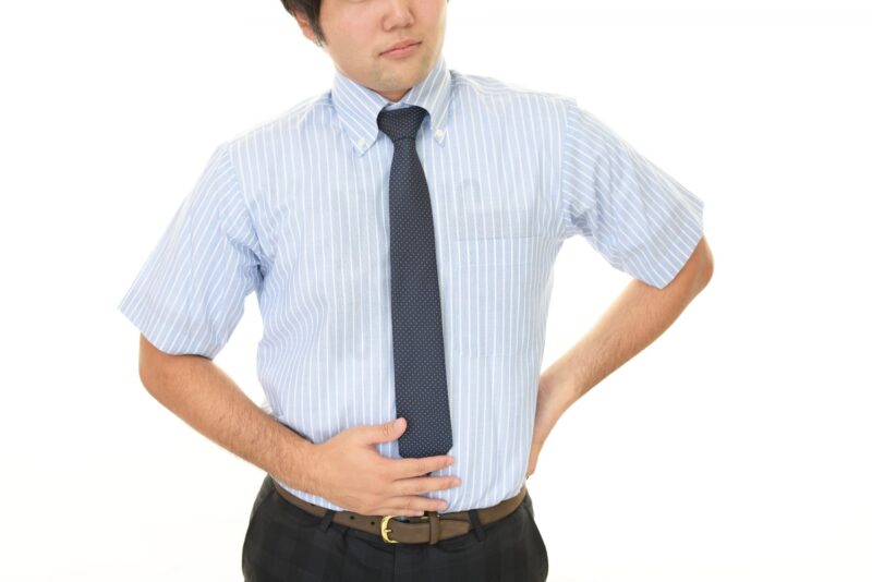 腹痛や胃の不調を感じている男性をイメージできる画像